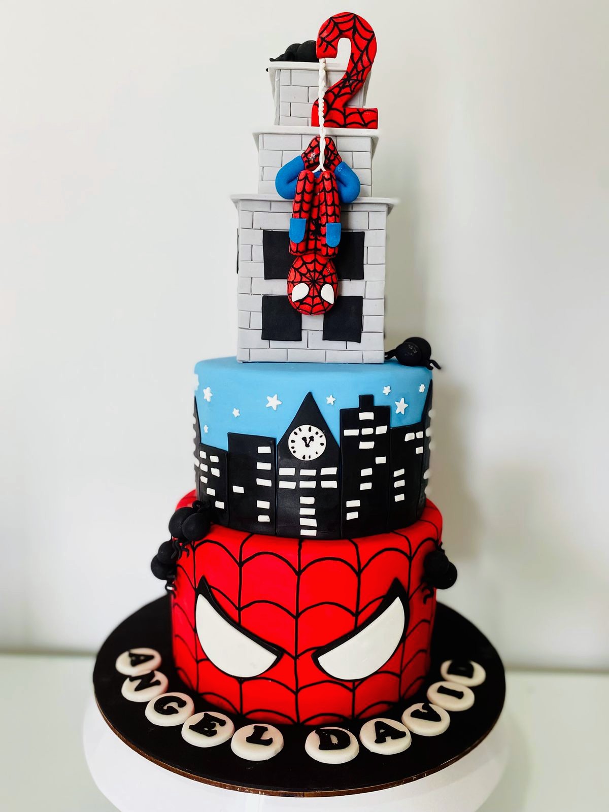 Torta infantil de superhéroe rojo y azul con edificios