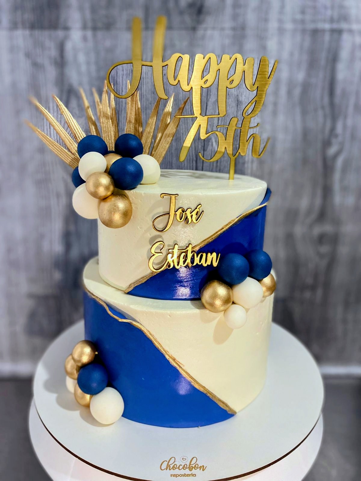Torta elegante azul rey, marfil y dorado para celebración de 75 años