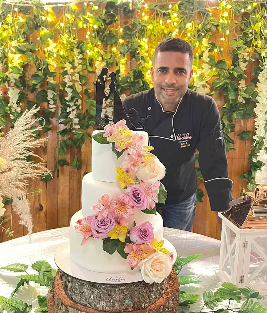 Chef Pastelero Erick R. con una torta de bodas de varios pisos