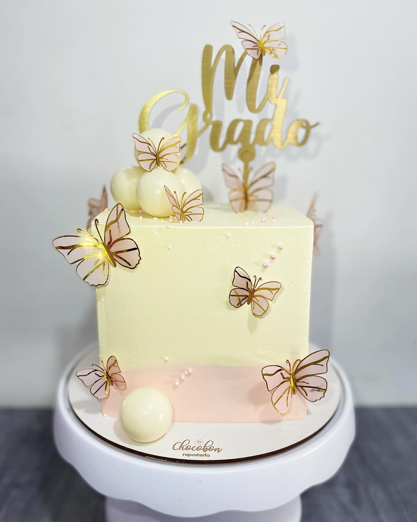 Torta de grado en marfil y rosa con mariposas doradas y topper Mi Grado
