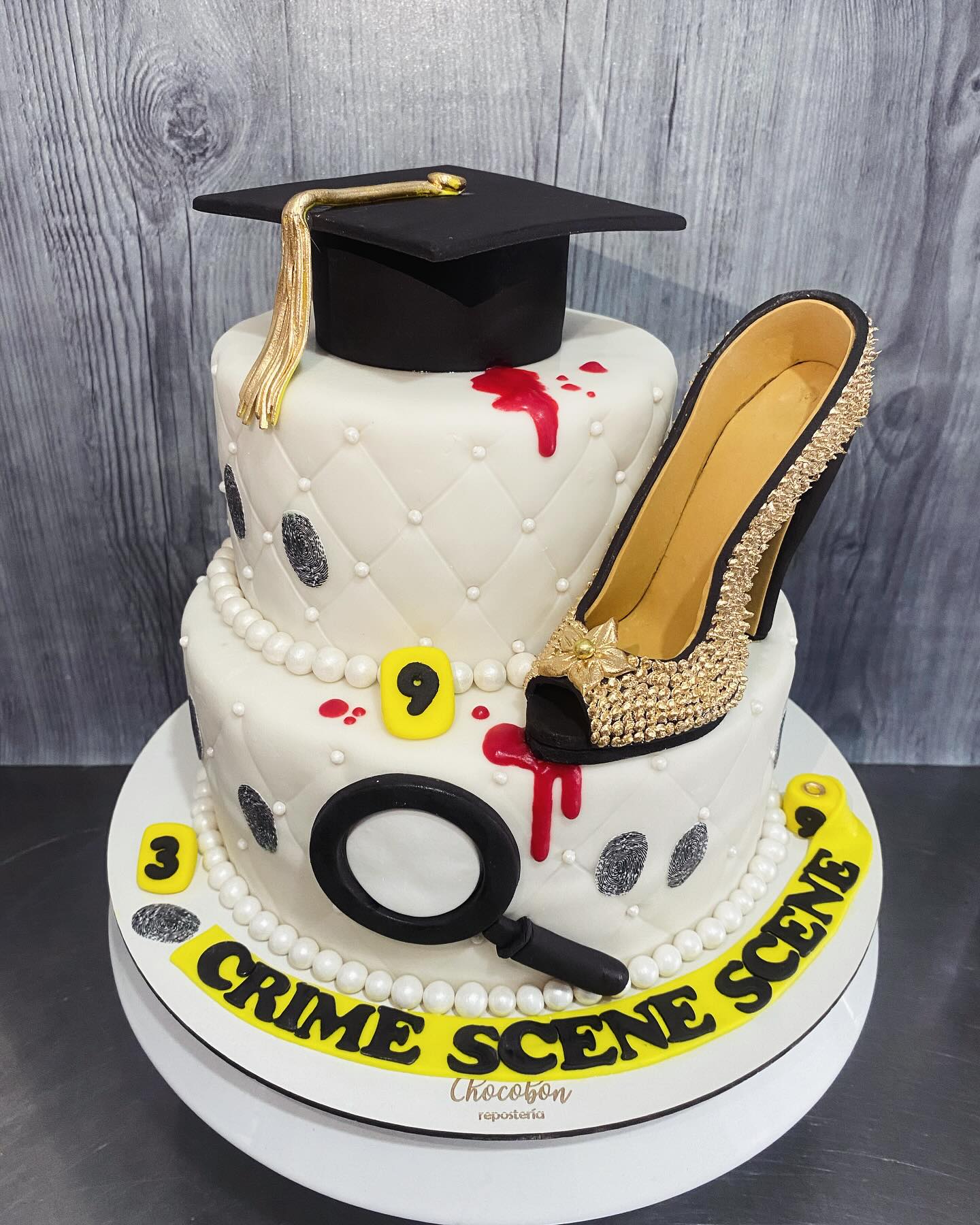 Torta de grado temática Crime Scene con birrete, taco dorado, lupa y huellas